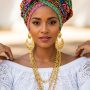 Woman wearing white lace Baiana-style blouse with colorful traditional Brazilian head wrap and gold jewelry