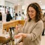 Woman spraying affordable long-lasting perfume on her wrist at a store fragrance counter