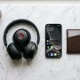 Premium black over-ear headphones resting on a modern wooden desktop stand.