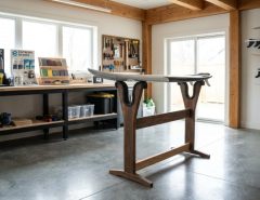 Surfboard repair stand holding shortboard in clean DIY garage workshop.