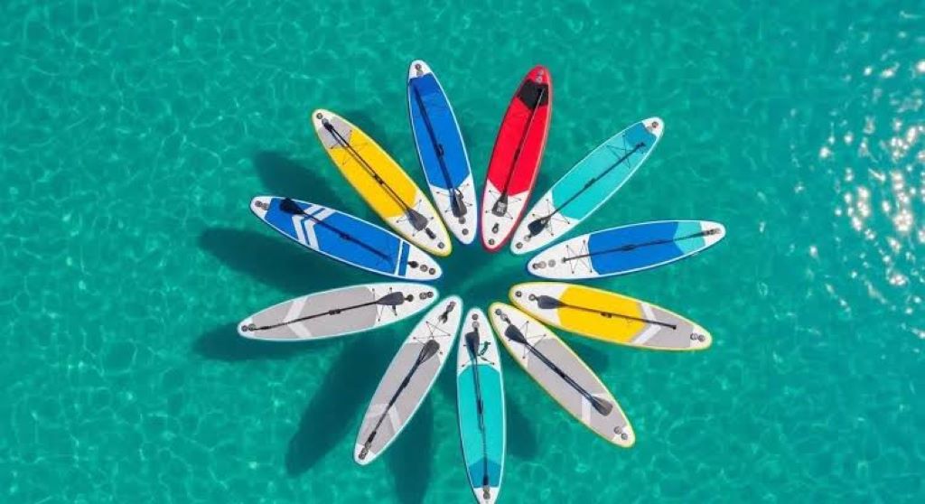 Close-up of affordable paddle board with paddle and pump on the beach