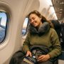 Woman sleeping comfortably with memory foam neck pillow on airplane.