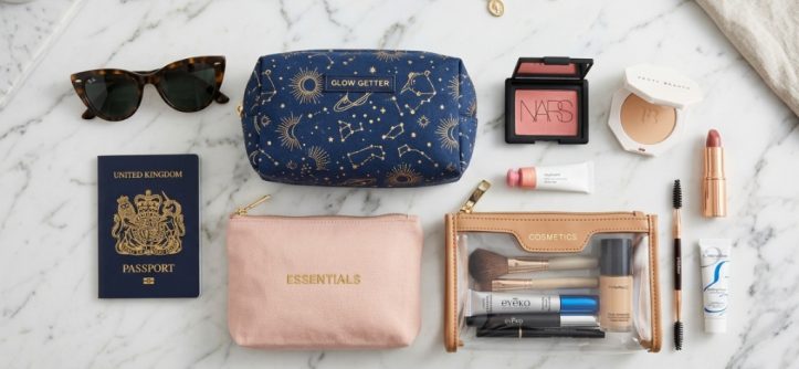 Organized makeup bags with travel-sized cosmetics on a vanity table.