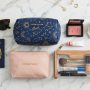 Organized makeup bags with travel-sized cosmetics on a vanity table.