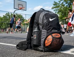 A mesh basketball backpack resting on a sunny outdoor court.