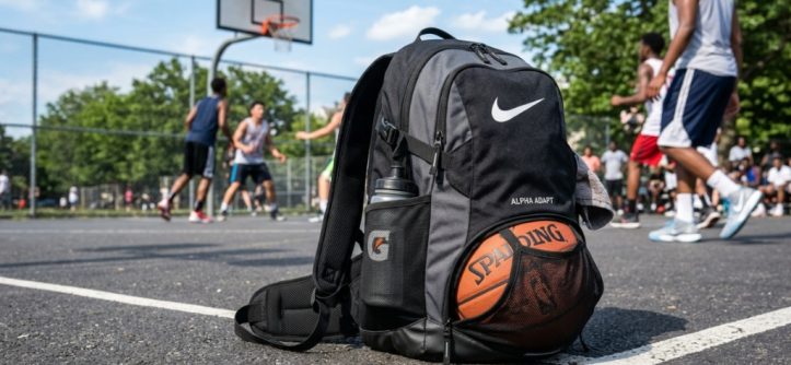 A mesh basketball backpack resting on a sunny outdoor court.