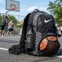 A mesh basketball backpack resting on a sunny outdoor court.