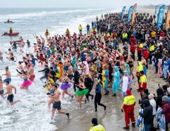 Crowd of swimmers entering the ocean on New Year's Day at a polar bear plunge event