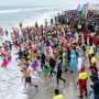 Crowd of swimmers entering the ocean on New Year's Day at a polar bear plunge event